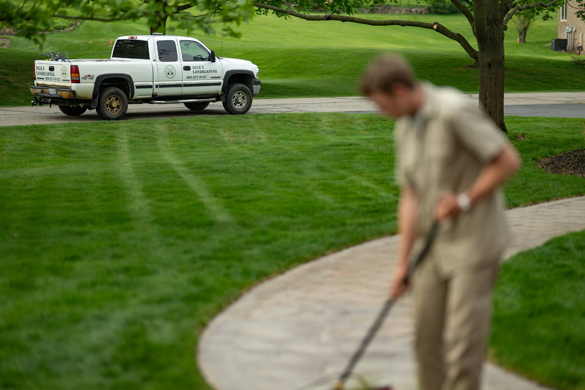 Freshly mowed lawn with mowing stripes and the Dick's Landscaping truck