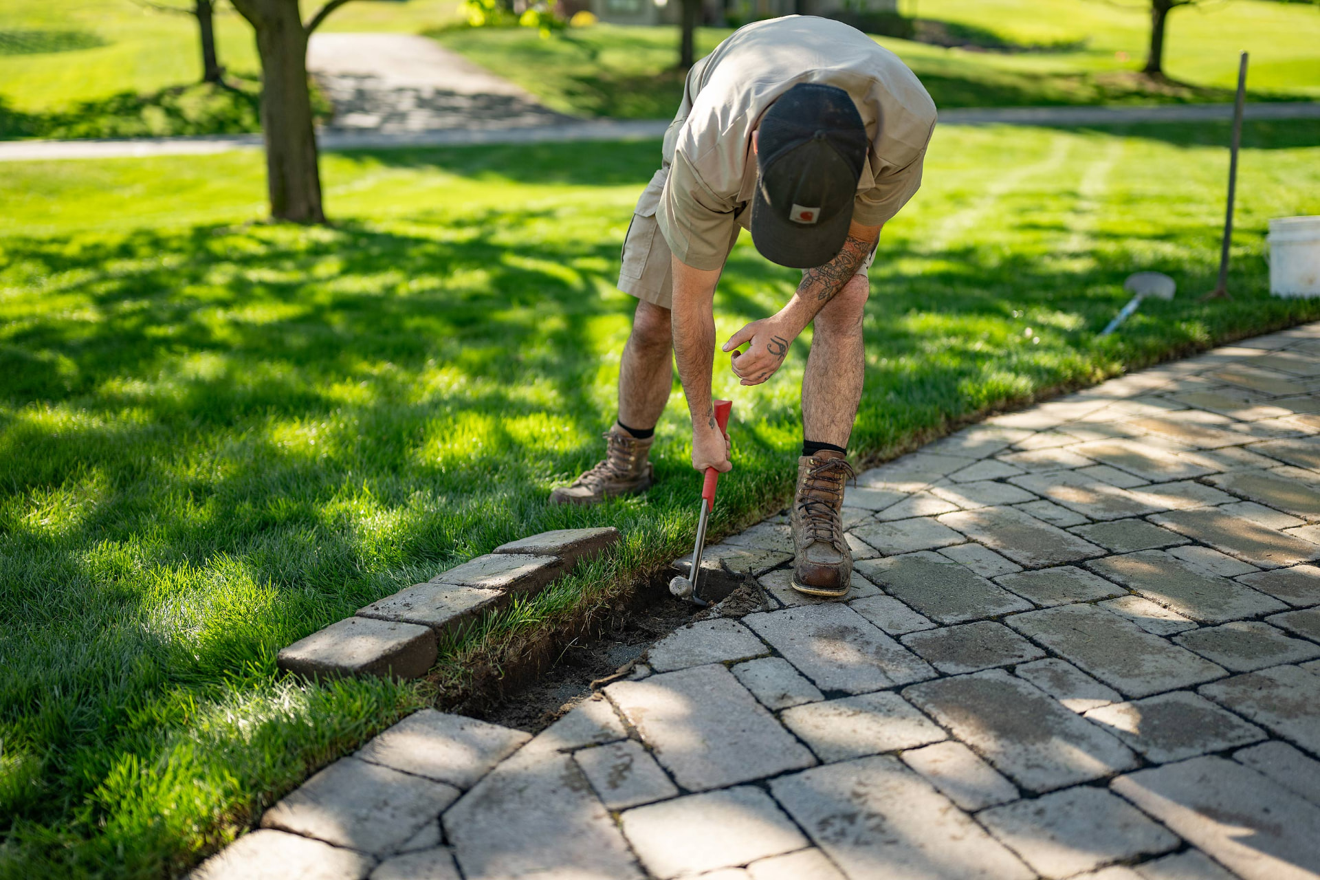 Crew member setting paver edge restraint along a stone walkway in Owosso, MI