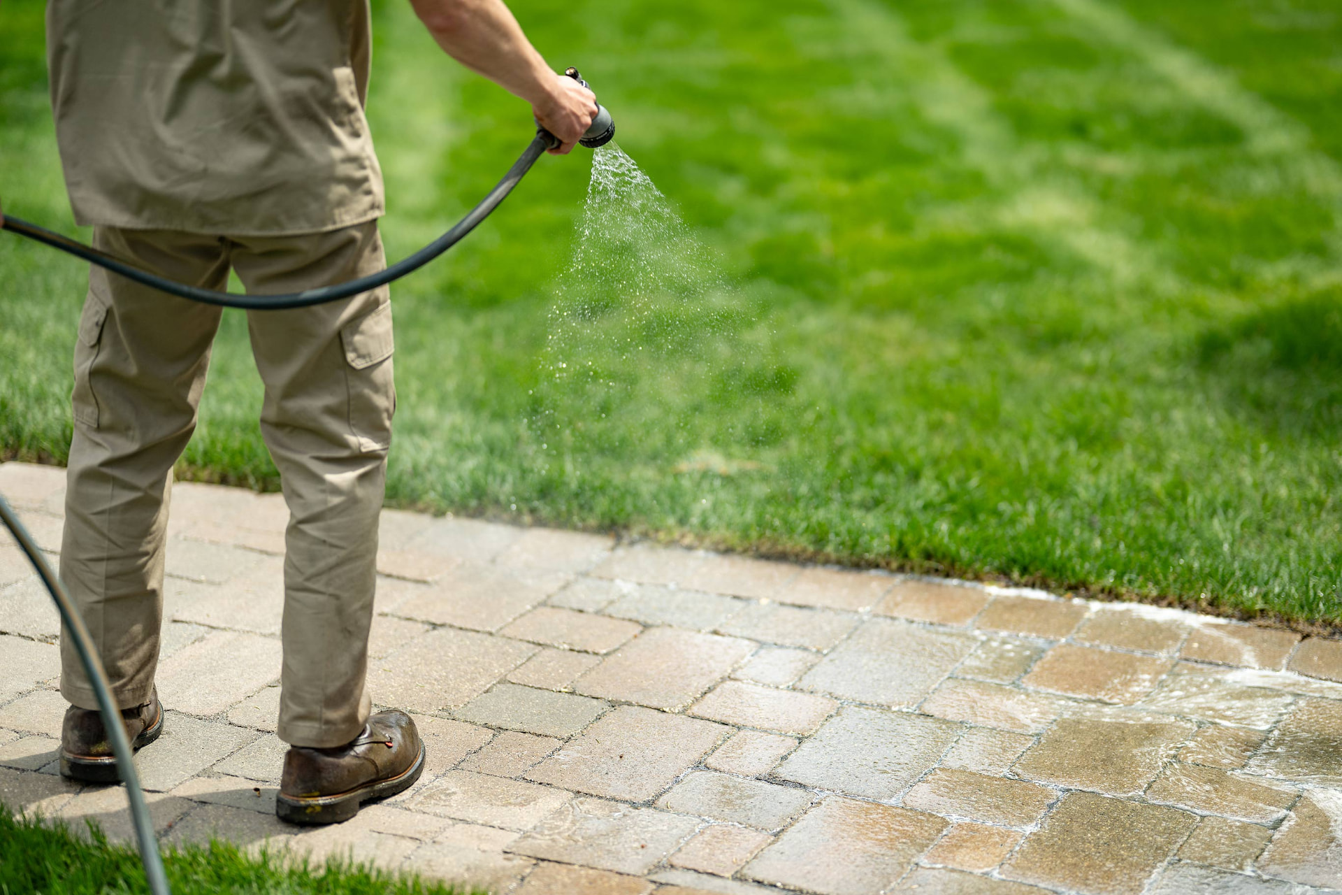 Watering in a newly finished paver walkway beside a striped lawn