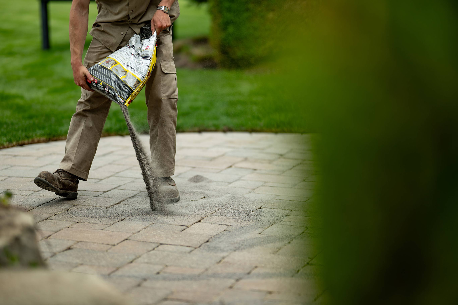 Polymeric sand poured into paver joints on a hardscape patio