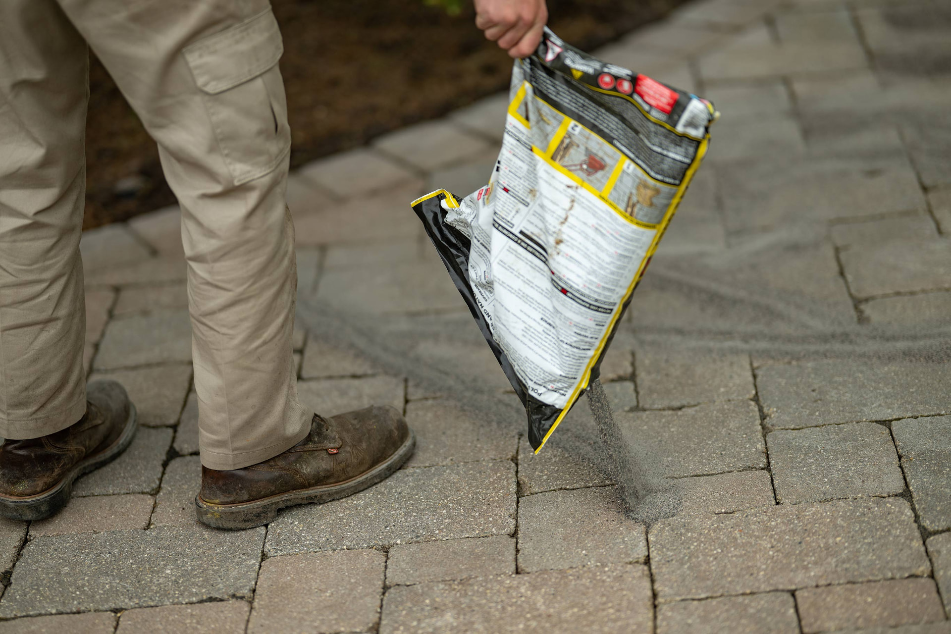 Close-up of jointing sand being spread across brick pavers